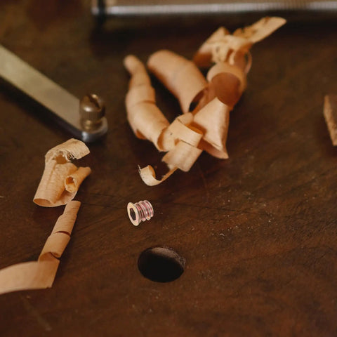 M6x10mm Countersunk Flange Wood Nut Inserts For Cabinets And Desks with wood shavings on a workbench