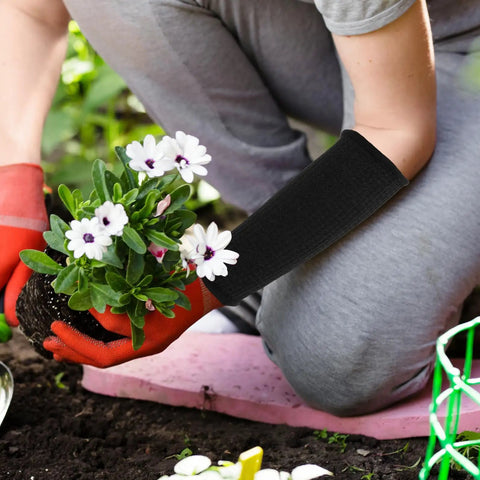 Person gardening while wearing Badass Cut Resistant Arm Sleeves Black Anti Cut Wrist Guards 2 Pack for protection.