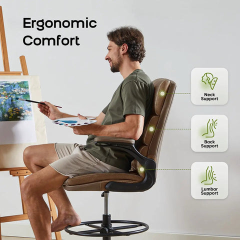 Man using tall drafting chair with padded flip up armrests, ergonomic leather backrest, and adjustable footrest ring for standing desks