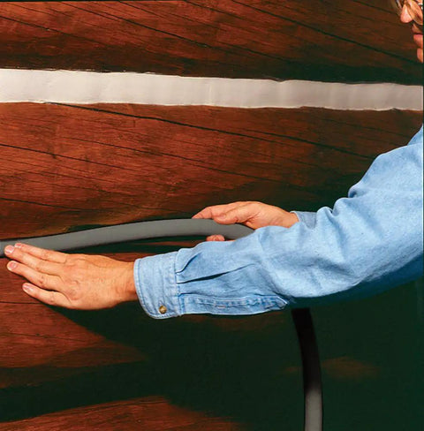 Person installing Pre Caulking Filler Rope Backer Rod Roll Gray, 100 Foot Long, Quarter Inch Width in wood panel gap.