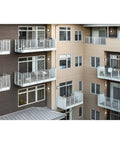 Apartment building with Outdoor Wall Light LED 13 Inch Textured Black With Integrated 3000K Glow, illuminating balconies.