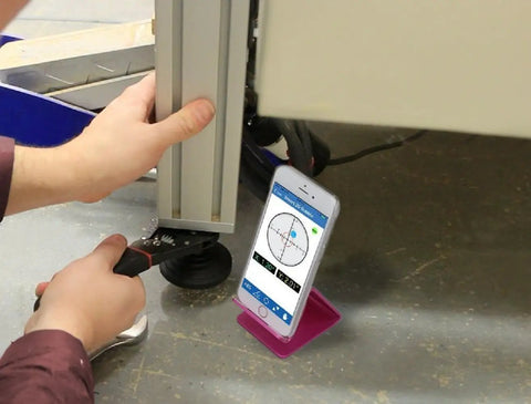 User aligning equipment using Smart Two Axis Bluetooth Digital Precision Level displayed on smartphone.