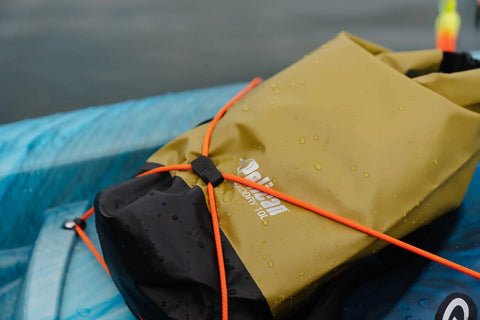 ExoDry 30L Large Drybag Waterproof With Roll Top Closure And Backpack Style Straps secured on kayak, olive with orange cords