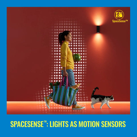 Woman walking with groceries under indoor spotlight with cat beside, promoting SpaceSense lights as motion sensors.