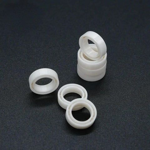 Top Shelf Zirconia Ceramic Deep Groove Ball Bearing 8 By 12 By 3.5 MM MR Series shown stacked and laid out on dark background.