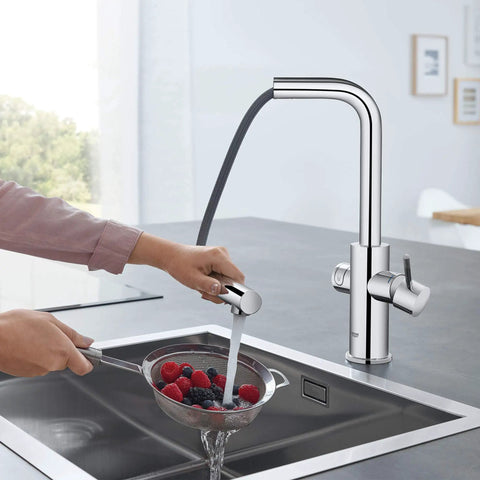 Clean Lines Single Handle Pull Out Kitchen Faucet With Laminar Spray Led Knobs For Chilled Sparkling Water Butter Smooth Pour 180 Swivel Spout in use, pouring water over berries.