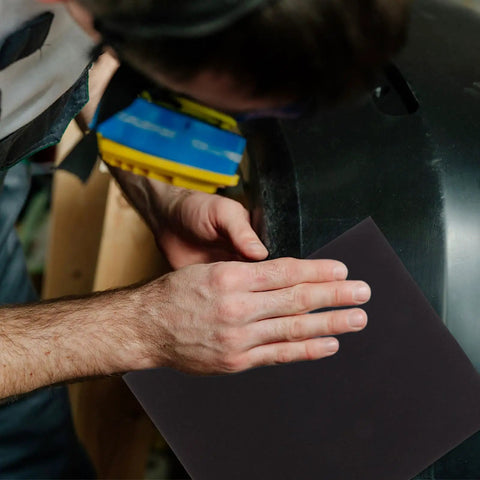 Rock Your DIY Game With This Tough 9 Sheet Black Wet Dry Sandpaper Assortment Pack Featuring Nine Grit Sizes For Smooth Woodworking, Crafting, And Polishing Jobs Using High Grade Silicon Carbide That Stays Durable Through Any Long Hustle You Might Have. Worker using black wet dry sandpaper on a surface.