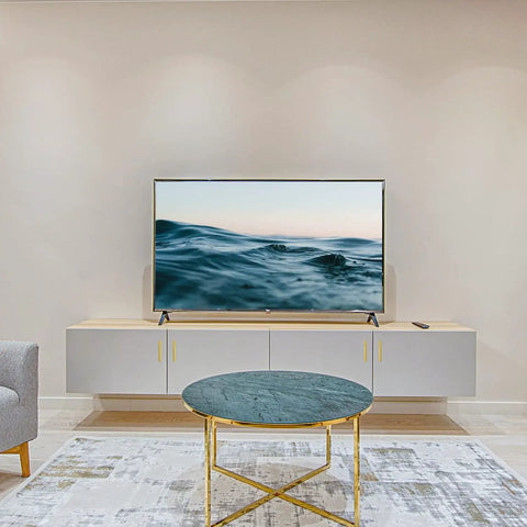 Modern living room with wall-mounted TV and minimalist furniture setup, including a round marble coffee table and sleek cabinetry.