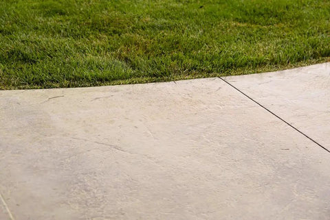 Kick Your Backyard Up A Notch With This Top Shelf Clear Satin Stamped Concrete Sealer applied on patio next to green grass.