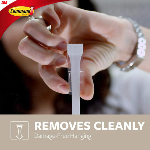 Person removing adhesive strip for Two Pack Key Rails With Twelve Strips Each Rail Holds Two Pounds Four Key Hooks Per Rail Damage Free Wall Mount No Tools Needed Easy Peel And Stick Keeps Keys Neat And Accessible In Home Office Garage.