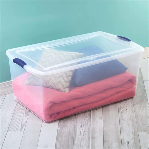 Badass 105 Quart Clear Plastic Storage Bin With Snug Blue Latching Lid Stackable Heavy Duty Box filled with bedding and pillows.