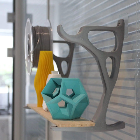 Heavy Hitter PLA Filament For 3D Printers 1.75mm 0.75kg Red Spool displayed with colorful 3D printed objects on a shelf.