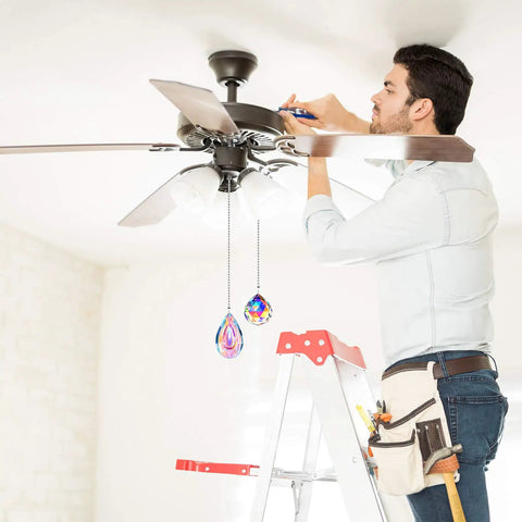 Person installing ceiling fan with Crystal Rainbow Ceiling Fan Pull Chain Set 20 Inch Extensions With Ball Connectors 4 Pack.