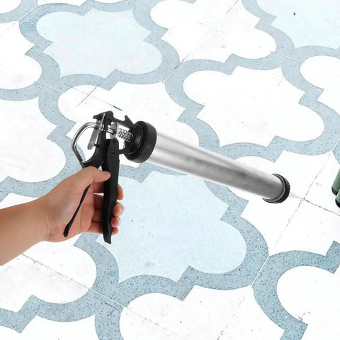Heavy Duty Metal Caulk Applicator With Thick Steel Rod For Concrete Seams And Tile Grout Lines Smooth Squeeze Sealant Gun in hand on tiled floor.