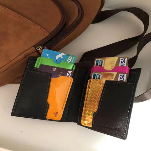 16 Piece RFID Blocking Sleeve Set With 12 Colorful Credit Card Protectors and a wallet beside a travel bag