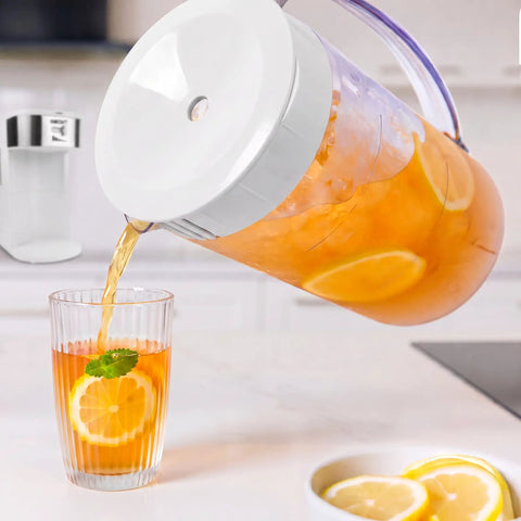 Generous 3 Quart White Stainless Steel Iced Tea And Cold Brew Coffee Brewing Pitcher pouring tea with lemon slices into a glass.