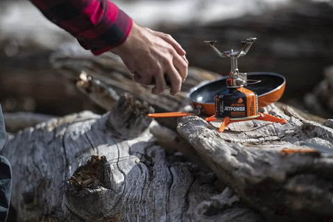 Ultralight Camping Stove That Boils Water In About 3 Minutes on a log, showing its compact design and stability for easy outdoor cooking.