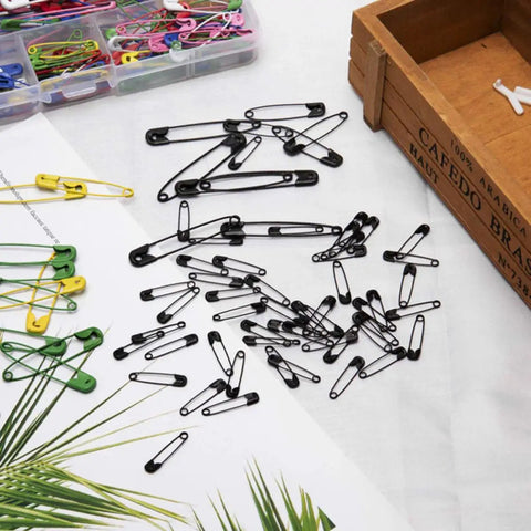 Kickass Assorted Steel Safety Pins Bulk Kit For Sewing Tailoring And Crafting Durable Multi Purpose Badge Clips and black safety pins scattered on a table