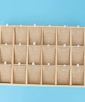 Top Shelf Solid Pine Wood Jewelry Organizer Tray With Eighteen Roomy Slots arranged on a blue background, showcasing burlap compartments.
