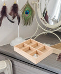 Slick Pine Wood Jewelry Organizer Tray With Six Compartments on vanity, holding pearl jewelry among decorative items.