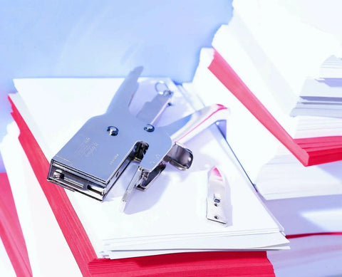 Heavy Duty Nickel Plated Staple Pliers With Attached Finger Stop And Standard Straight Anvil on stacks of paper sheets.