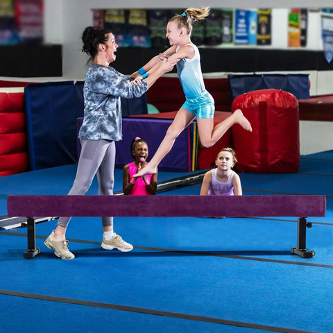 Next Level Gymnastics Training With This Heavy Duty 7.5 Ft Adjustable Balance Beam Featuring Quick Height Shifts And Rolling Stands, girl leaping off beam.