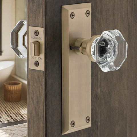 Crystal Door Knob With Long Back Plate In Waldorf And New York Style Finish on wooden door, antique brass plate visible