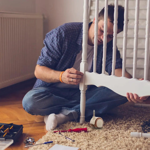 Man assembling a baby bed using Flex Ride Caster Wheels With Secure Safety Brakes Whisper Soft Swivel Rubber Furniture Casters.