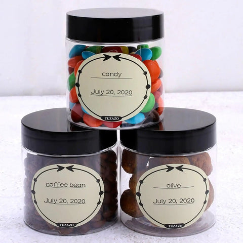 12 Pack 4 Oz Clear Plastic Sample Jars With Heavy Duty Black Screw Top Lids filled with candy, coffee beans, and olives.