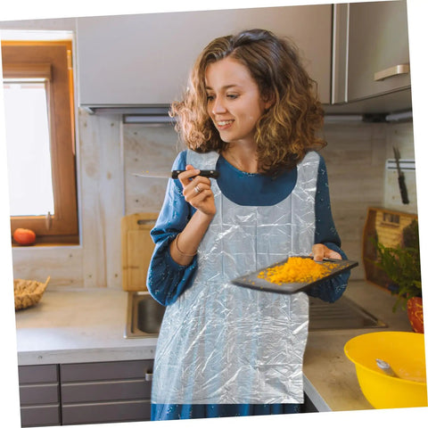 Get Ready To Tackle The Mess With This Slick Rock Solid Pack Of Twenty Five Chemical Resistant Waterproof Sleeveless Aprons In Transparent Plastic Perfect For Kitchen Grilling And Dirty Chores Giving You Zero Stress And Total Victory Today. Clear plastic apron worn by a woman in a kitchen while chopping food.