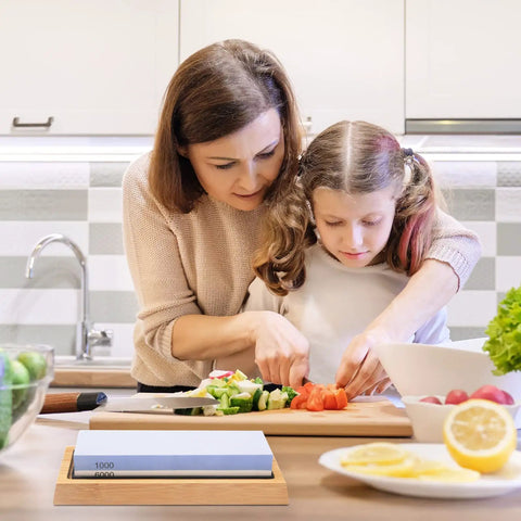 Mother and daughter cutting vegetables in kitchen with Double Sided Knife Sharpener Kit 1000 6000 Grit With Slip Resistant Bamboo Base And Angle Guide.