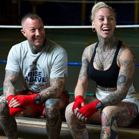 Two athletes sitting in a boxing gym wearing Premium Gym Grade Four Way Stretch Boxing Hand Wraps In Black.