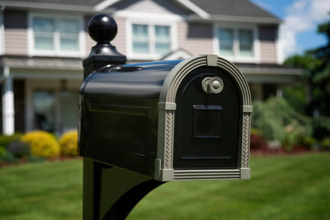 Photo of a large steel post mount mailbox in black with brushed nickel finish, placed outdoors with a house in the background.