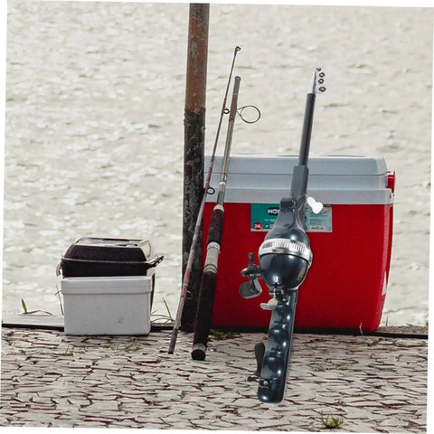 Pocket Size Baitcasting Rod Kit With Telescopic Rod And Included Reel And Line next to tackle boxes by a lake