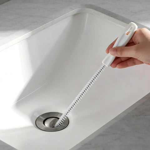 Flexible Drain Snake Cleaner Brush That Kicks Out Greasy Gunk Reusable Spiral Hair Removal Tool With Comfort Grip Handles For Sinks Showers And Bathtubs In White in use in a sink with a hand holding it.
