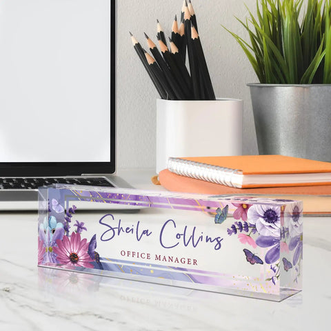 Personalized Acrylic Desk Name Plate With Purple Flower Design on office desk next to laptop, showcasing customized name and title.