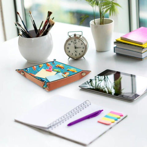 Slick Microfiber Leather Valet Tray For Nightstand And Desk on a table, featuring a cartoon car grid print with papers.