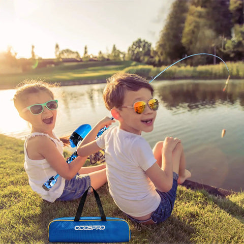 Kids enjoy fishing by a lake using Best Value All In One Kids Fishing Pole Starter Kit With Tackle Box Reel Practice Plug And Beginner Guide Plus Travel Bag For Boys And Girls Ages Three To Fifteen, bright day.