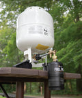 One Pound Propane Refill Kit For Refillable Tank shown with stabilizing feet on wooden table in outdoor setting