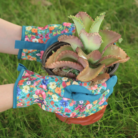 Hands wearing Womens Gardening Gloves With Printed Design And Touchscreen Grip For Thorn Proof Puncture Resistant Work Gloves holding a plant.
