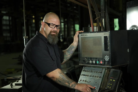 Man wearing Straight Up Reliable Goliath Safety Glasses Featuring Clear Polycarbonate Lenses working on machinery controls.