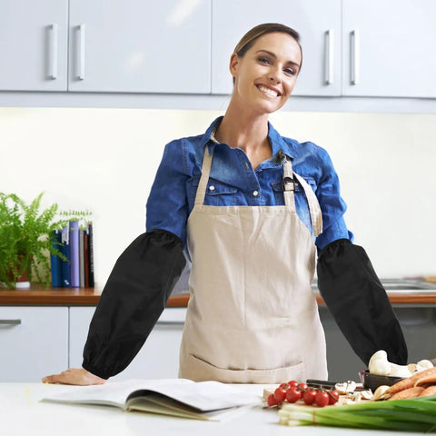 Woman wearing Slick Shield Waterproof Arm Sleeves in black while cooking in the kitchen, showcasing heavy duty oilproof protection.