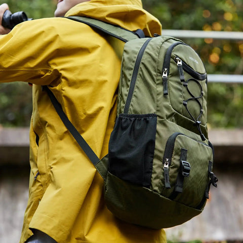 Person wearing a green Lightweight 35L Foldable Hiking Backpack For Men And Women, Waterproof Outdoor Daypack for travel and camping.