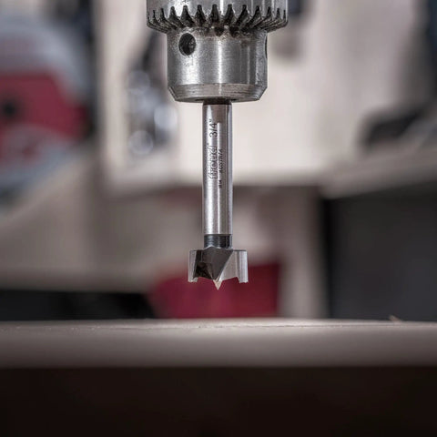 Close-up of PB-005 Three Quarter Inch Forstner Bit With Three Eighths Inch Shank in drill, cutting wood.
