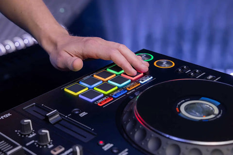 Close-up of hand using Four Deck All In One DJ System With A 10.1 Inch Touchscreen with illuminated performance pads and controls.