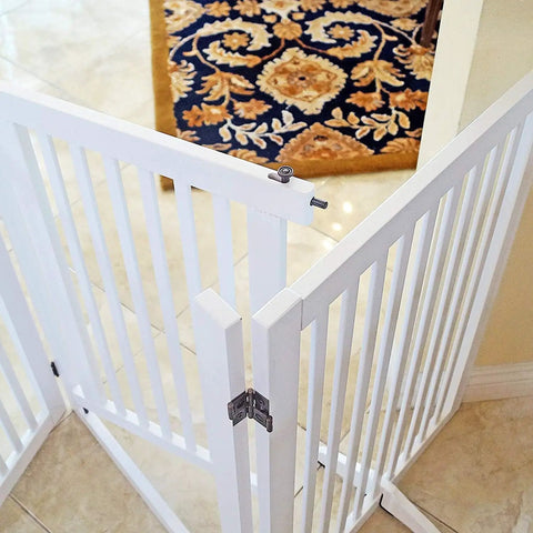White wooden pet gate system indoors, hinges visible, positioned on tiled floor next to ornate rug corner.
