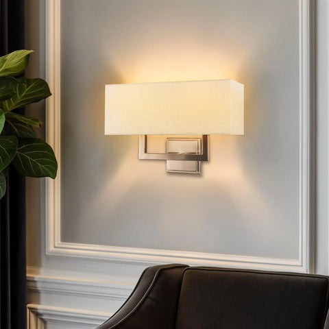 Haven 16 Inch 2 Light Totally Chic Modern Wall Sconce With White Fabric Shade For Bathrooms And Hallways Mid Century Rectangular Silver Wall Light In Brushed Nickel Finish shown mounted on a wall.