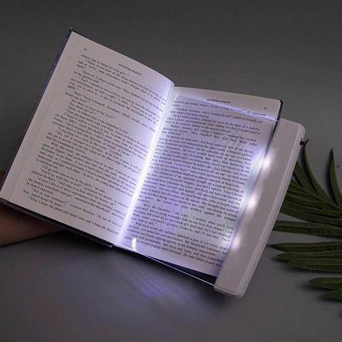 Flat Page Book Light With Clear LED Panel for reading in bed at night, illuminating a full page with cozy warm glow.