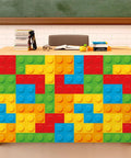 9 Foot Building Block Table Skirt Bringing Sweet Brick Vibes To Teachers Desks And Classroom Workstations For Back To School Setup And Quick Office Or Cabinet Decor Accents on a desk with colorful brick design.