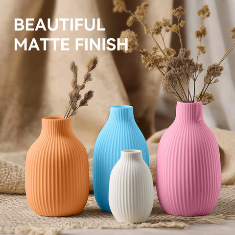 Front view of four matte ribbed vases in orange, blue, white, and pink with dried stems
